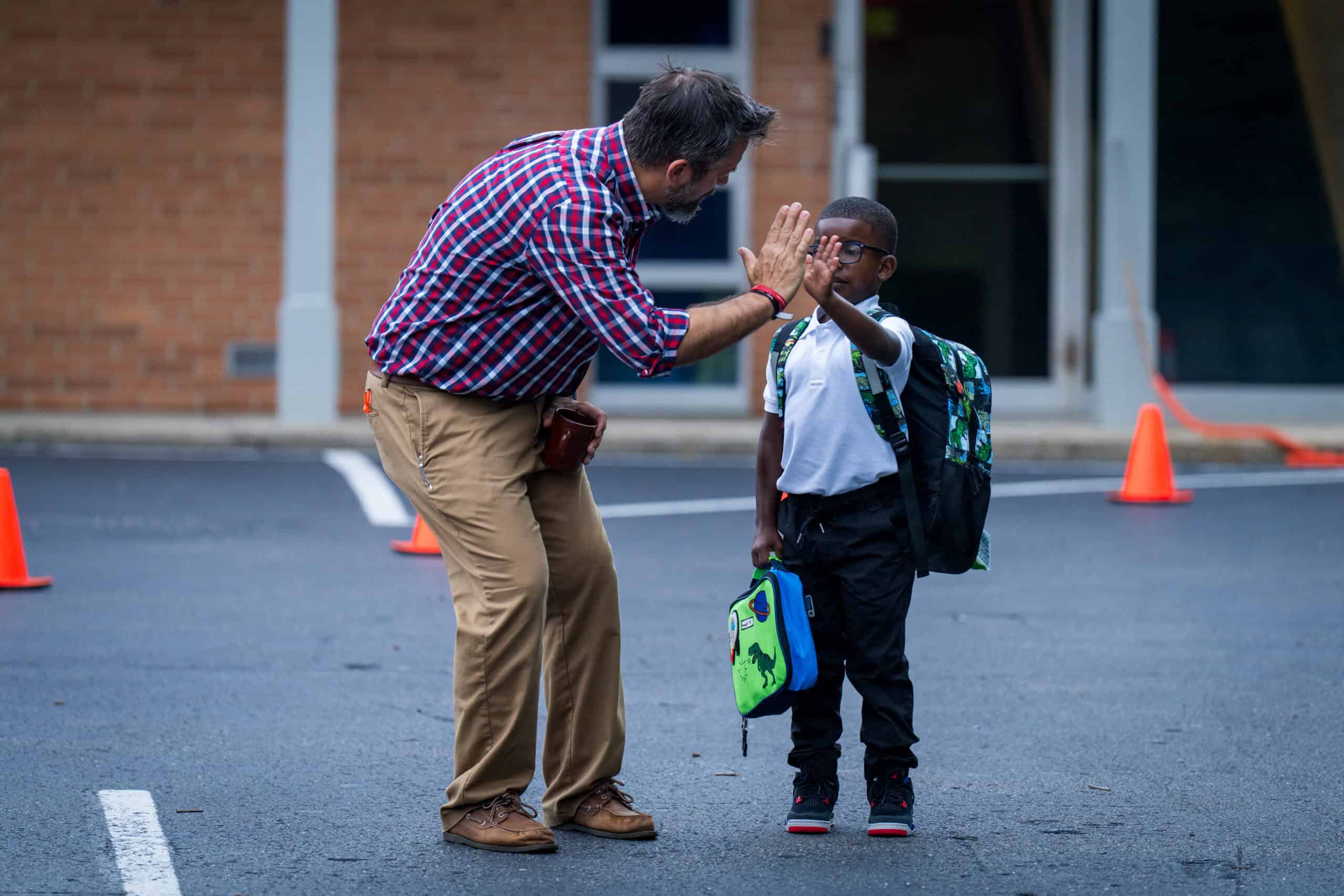 Teacher greeting student with a high-five at morning drop-off